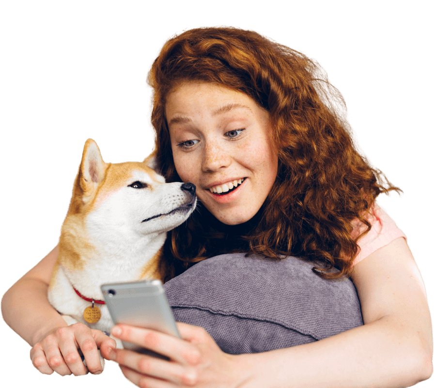 red-haired woman looking pleasantly surprised at her phone while holding her shiba inu dog on a transparent background